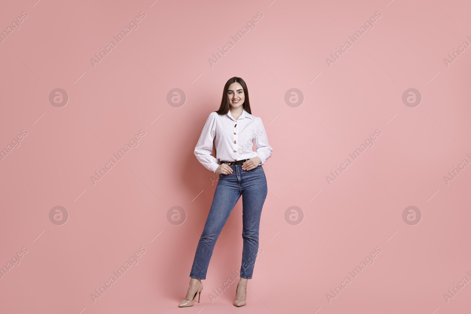 Photo of Smiling woman in stylish jeans on pink background