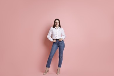 Smiling woman in stylish jeans on pink background