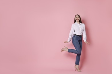 Photo of Happy woman in stylish jeans on pink background. Space for text