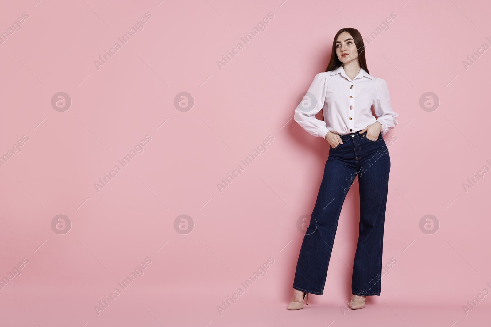 Photo of Woman in stylish jeans on pink background. Space for text