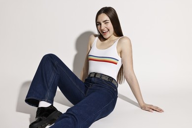 Happy woman in stylish jeans posing on light background