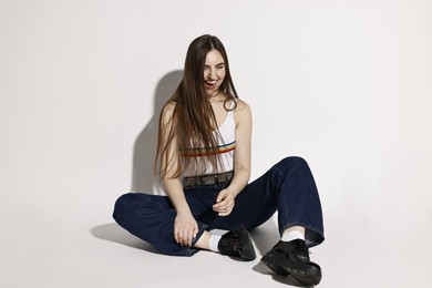 Photo of Happy woman in stylish jeans on light background