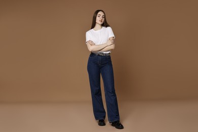 Photo of Beautiful young woman in stylish jeans on brown background