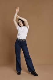 Photo of Woman in stylish jeans posing on brown background