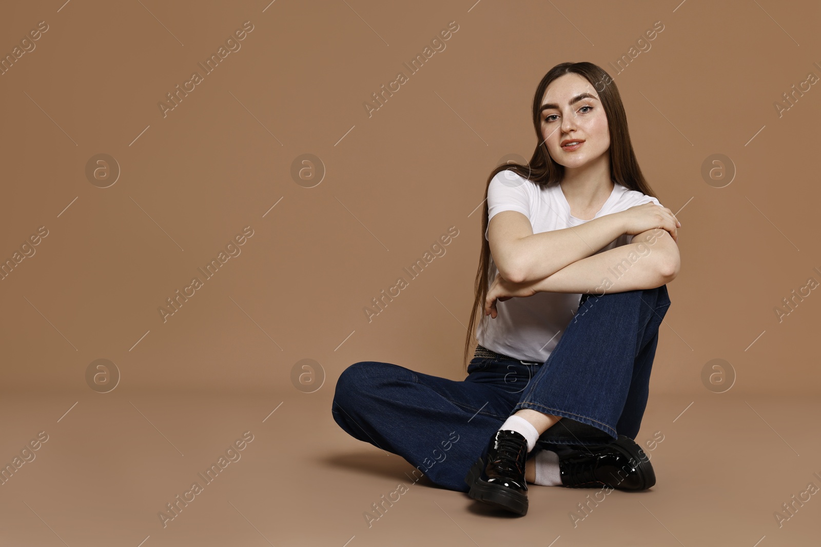 Photo of Woman in stylish jeans on brown background. Space for text