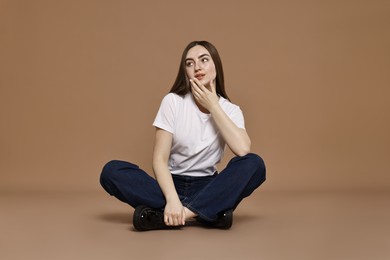 Photo of Beautiful young woman in stylish jeans on brown background