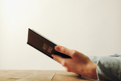 Photo of Woman with Holy Bible at wooden table, closeup