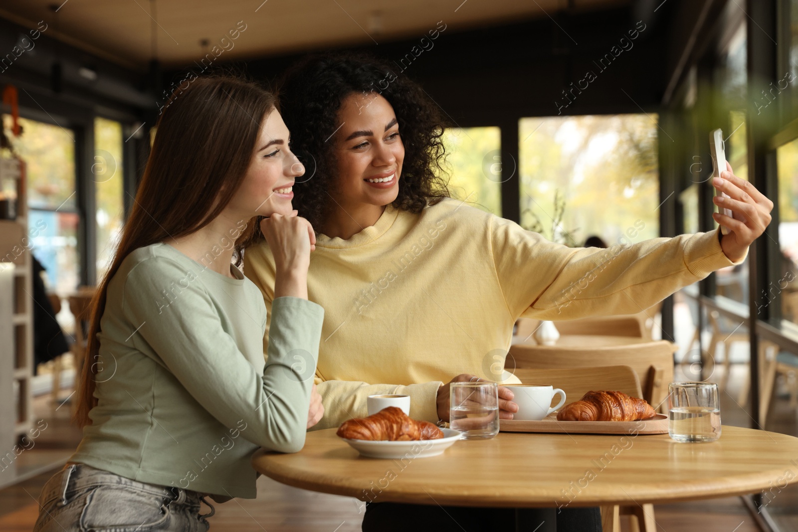 Photo of Happy friends taking selfie during coffee meeting in cafe