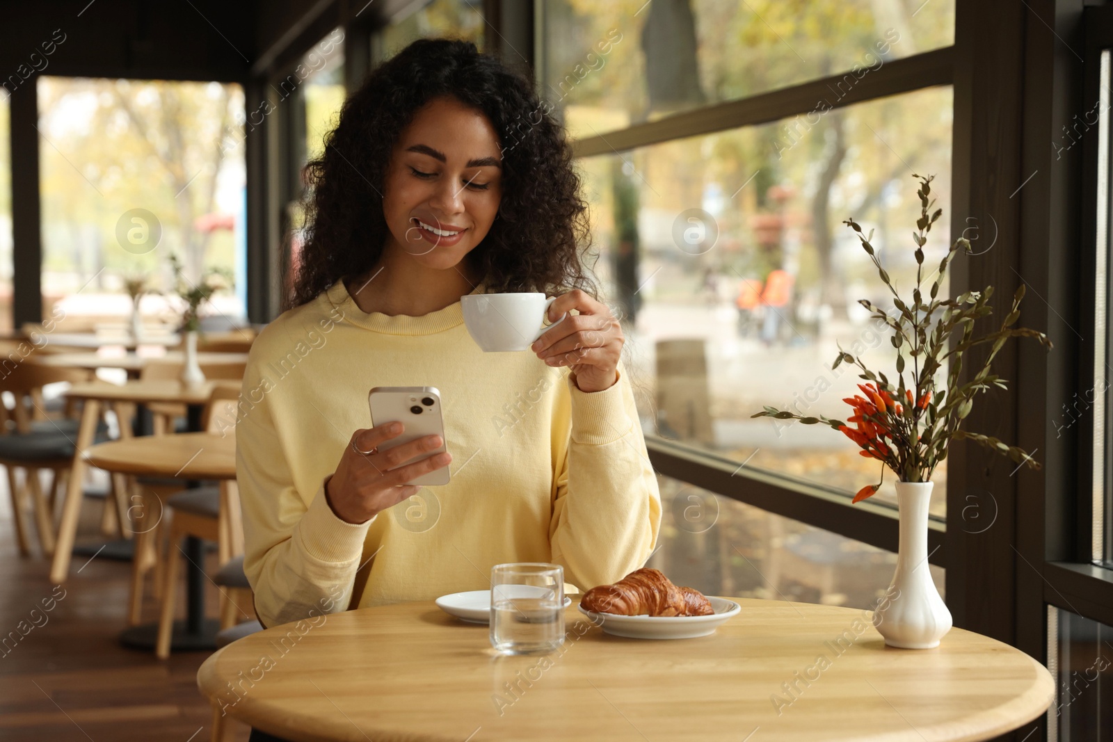 Photo of Woman using smartphone during her coffee break in cafe