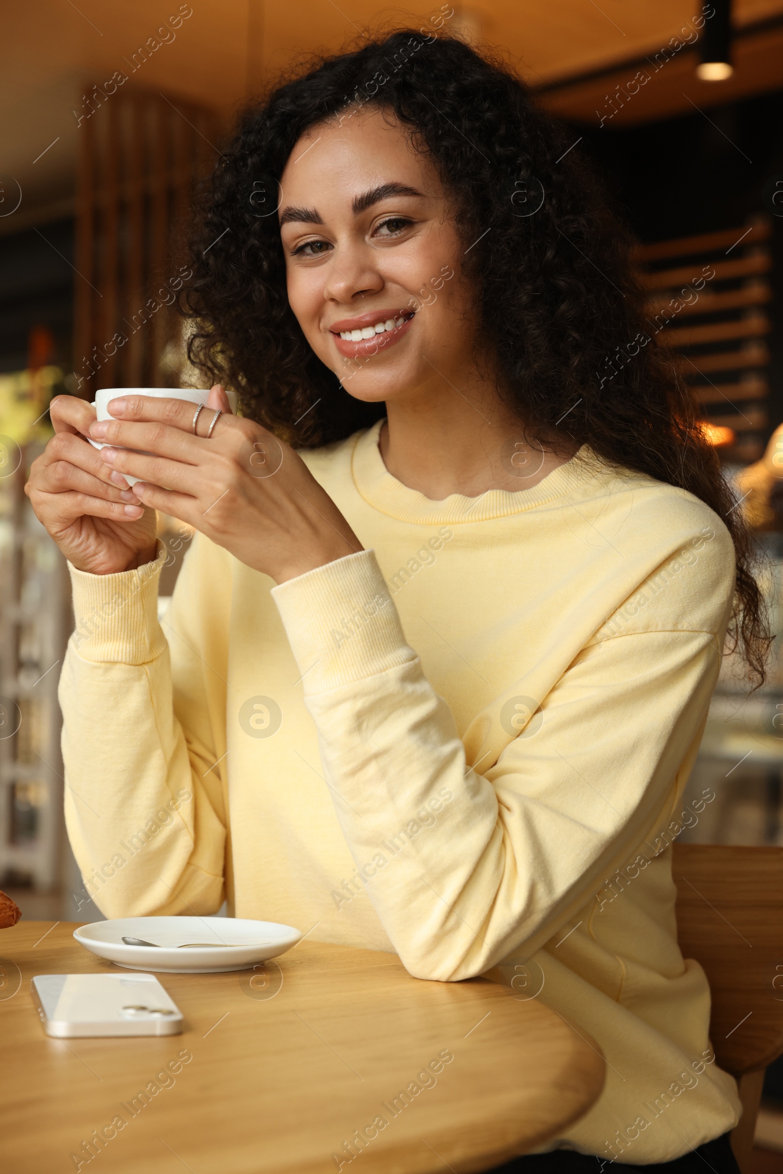 Photo of Woman with cup of coffee at table in cafe