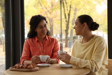 Photo of Happy women with coffee drinks chatting in cafe