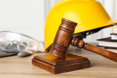 Photo of Accident at work. Gavel, safety equipment and stack of books on wooden table, selective focus