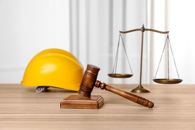 Photo of Accident at work. Gavel, hardhat and scales on wooden table