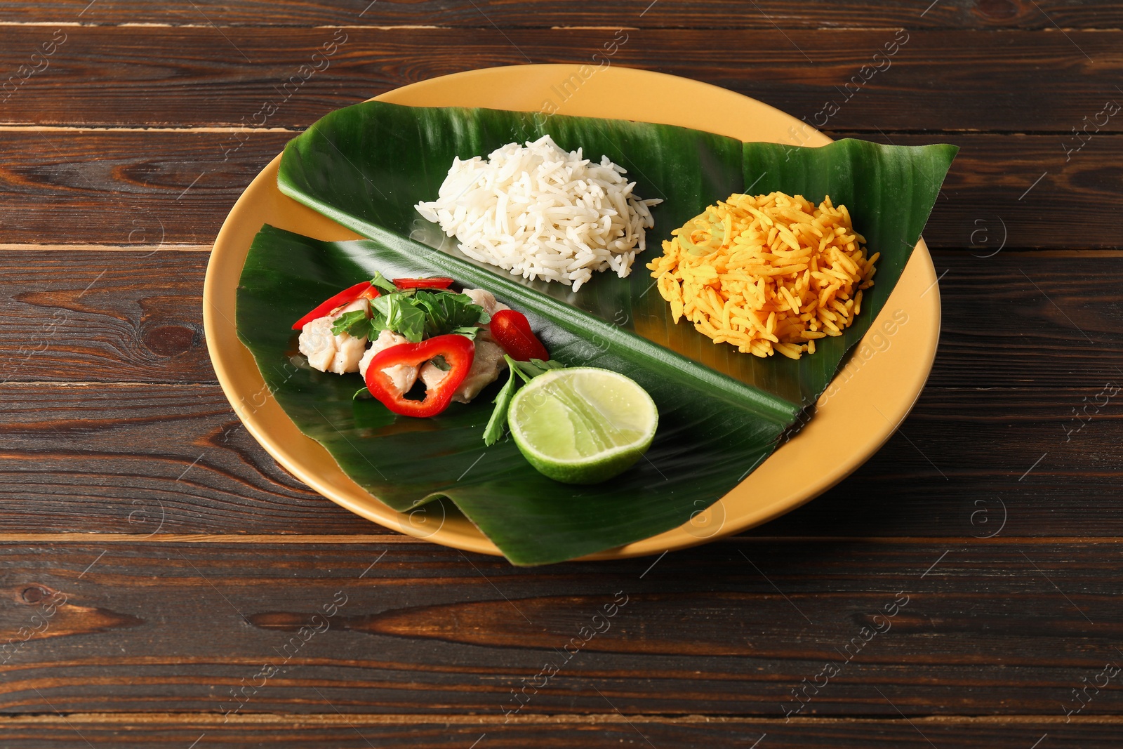 Photo of Cut banana leaf with different food on wooden table, above view