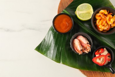 Photo of Cut banana leaf with different food and sauce on white marble table, top view. Space for text