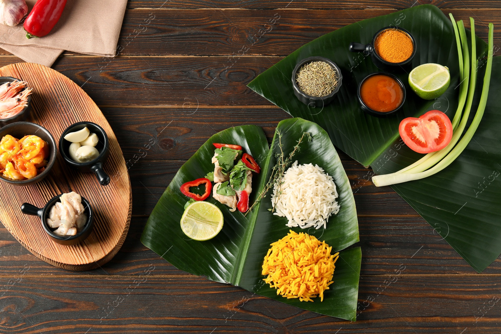 Photo of Flat lay composition with cut banana leaves, different food, spices and sauce on wooden table