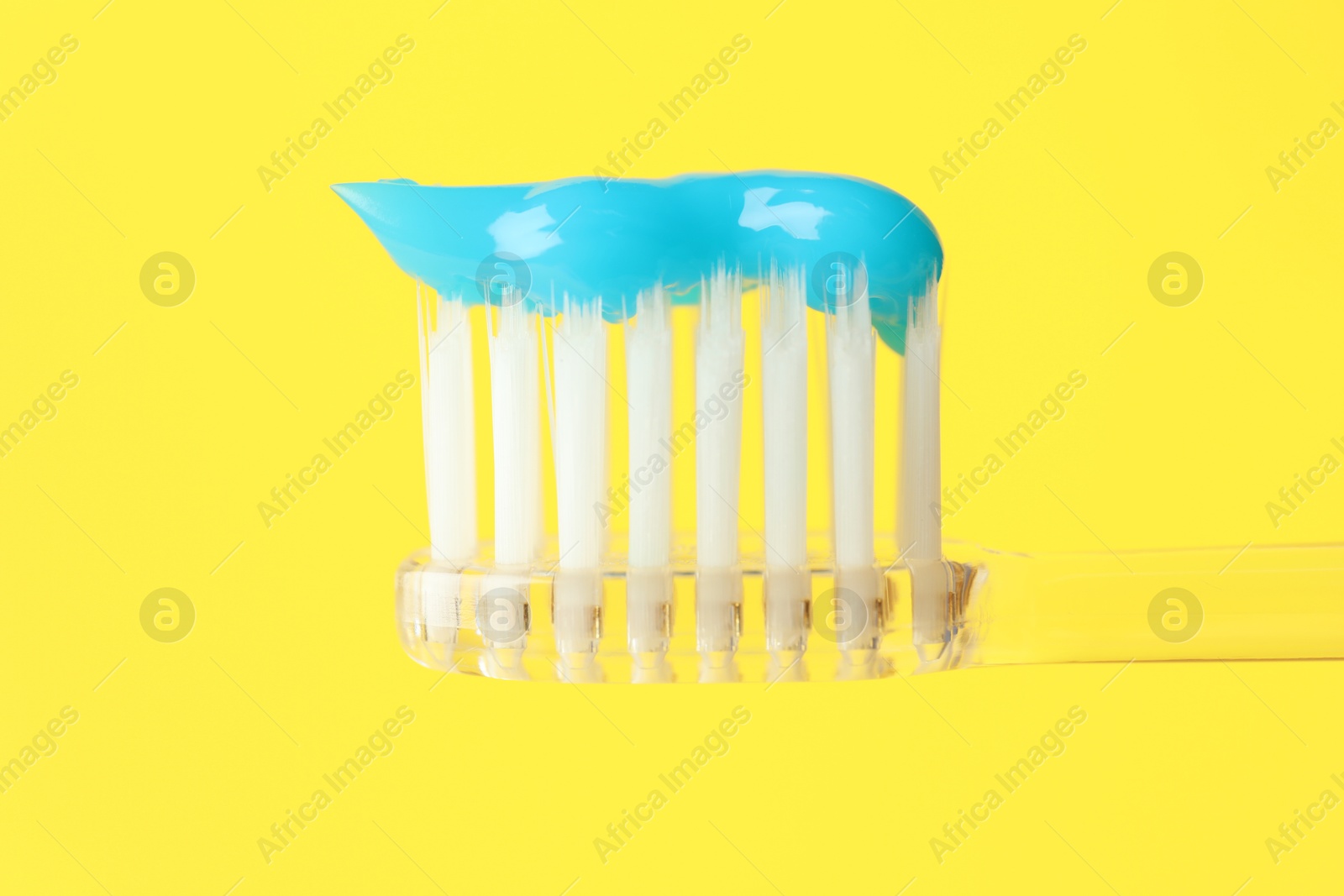 Photo of Toothbrush with toothpaste in air on yellow background, closeup