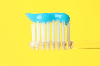 Photo of Toothbrush with toothpaste in air on yellow background, closeup