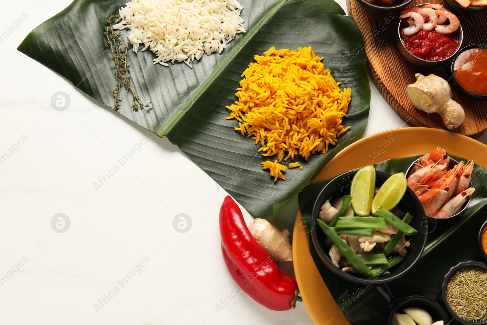 Photo of Cut banana leaves with different food, spices and sauce on white table, flat lay