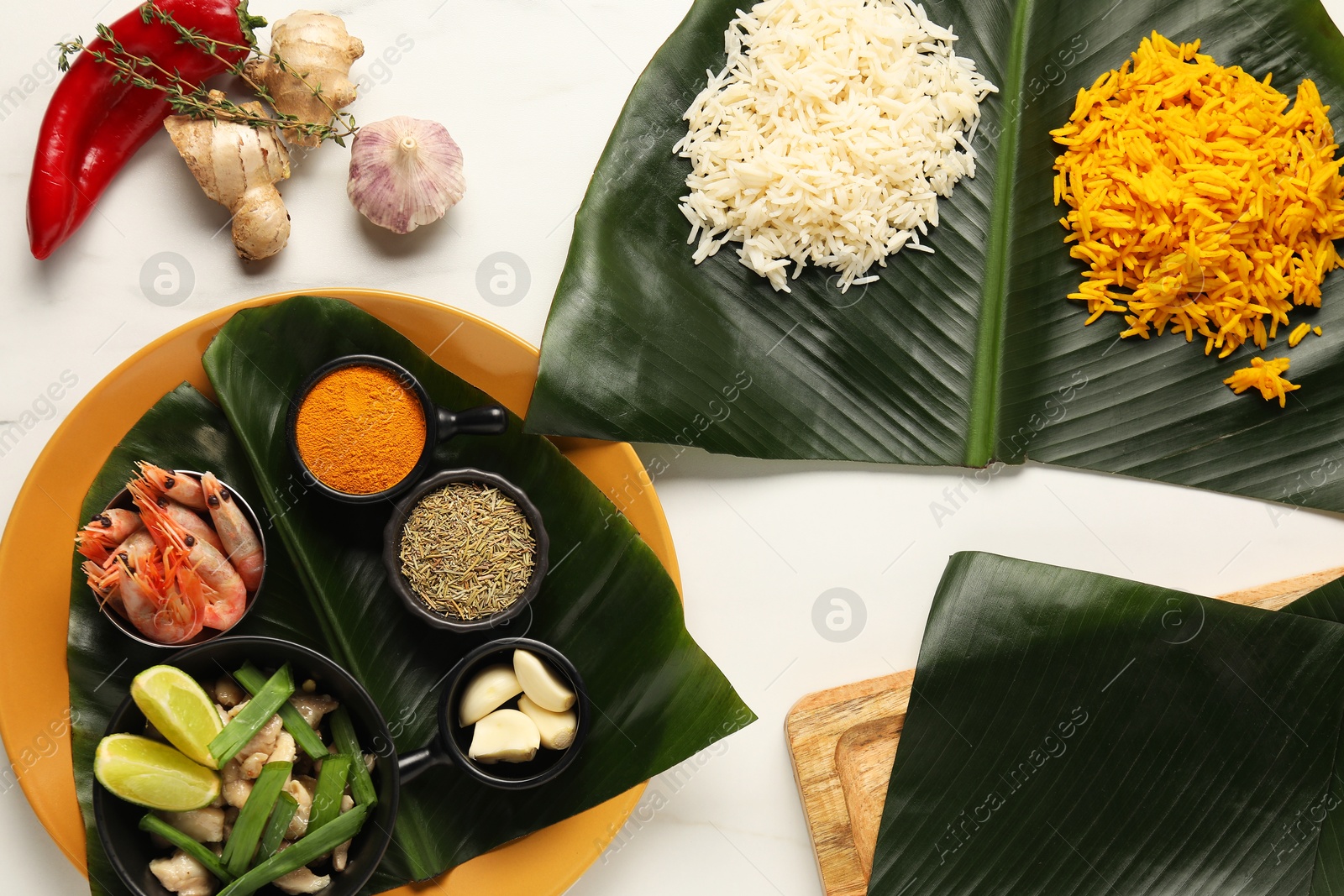 Photo of Cut banana leaves with different food and spices on white table, flat lay