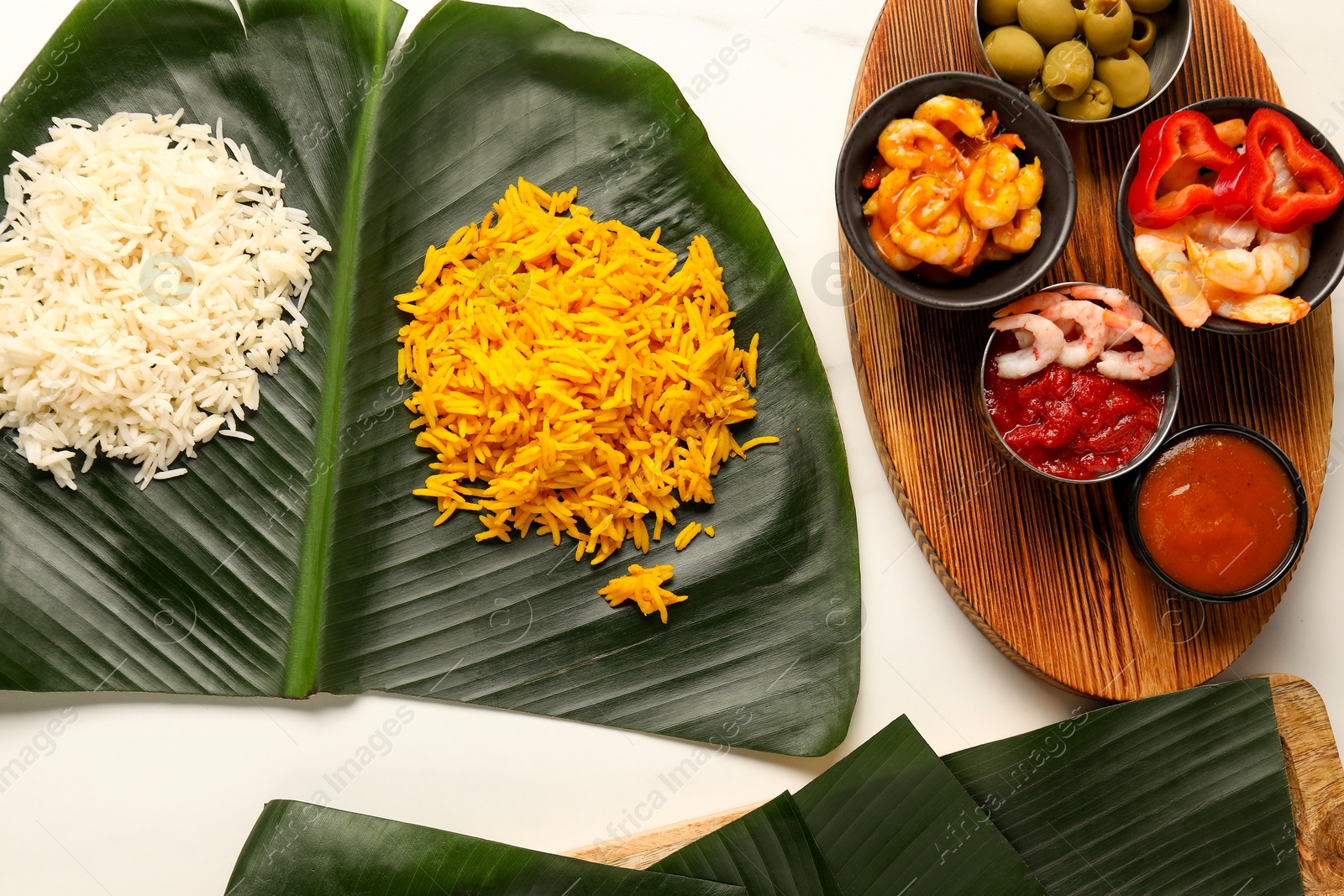 Photo of Cut banana leaves with different food and sauce on white table, flat lay