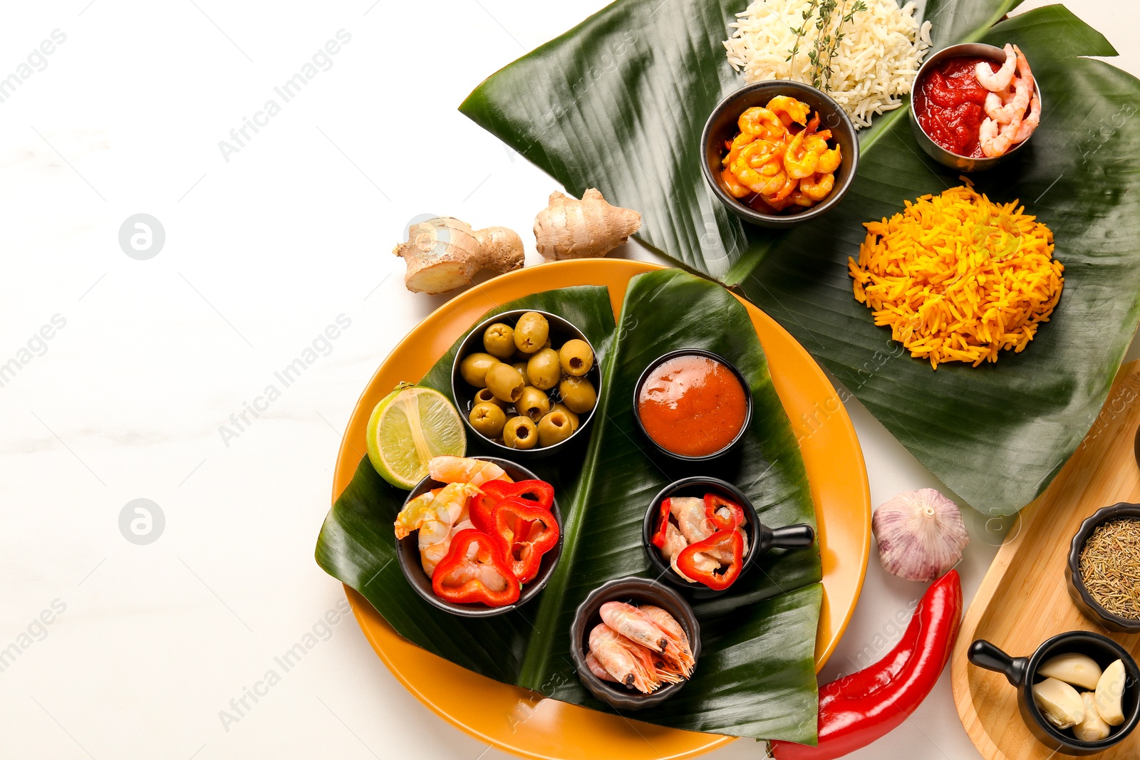 Photo of Cut banana leaves with different food, spices and sauce on white marble table, flat lay. Space for text