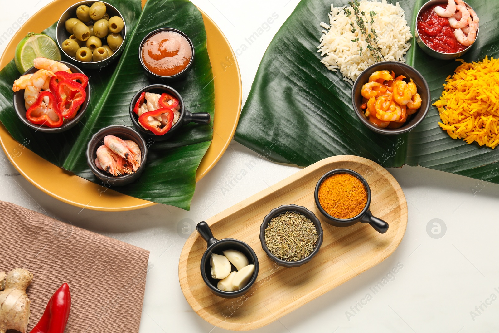 Photo of Cut banana leaves with different food, spices and sauce on white table, flat lay. Healthy eco serving