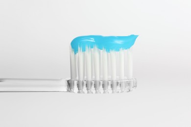 Photo of One toothbrush with toothpaste in air on white background, closeup