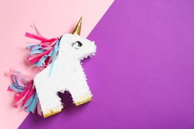 Photo of Bright pinata in shape of unicorn on color background, top view. Space for text