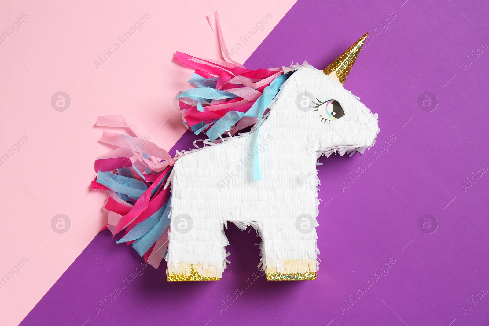 Photo of Bright pinata in shape of unicorn on color background, top view