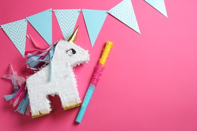 Photo of Bright pinata in shape of unicorn and party accessories on pink background, top view. Space for text