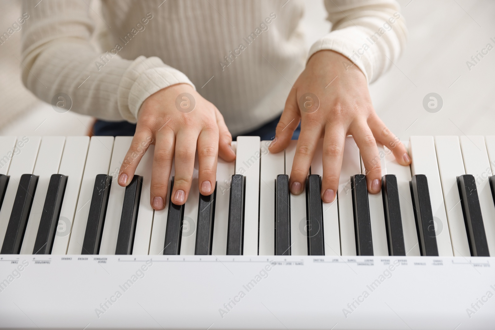 Photo of Girl playing synthesizer indoors, closeup. Electronic musical instrument