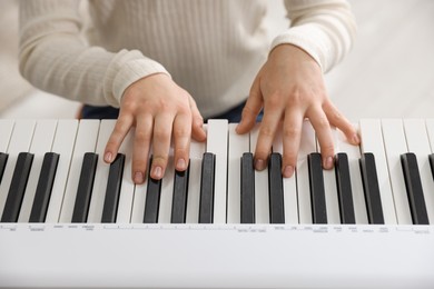 Girl playing synthesizer indoors, closeup. Electronic musical instrument