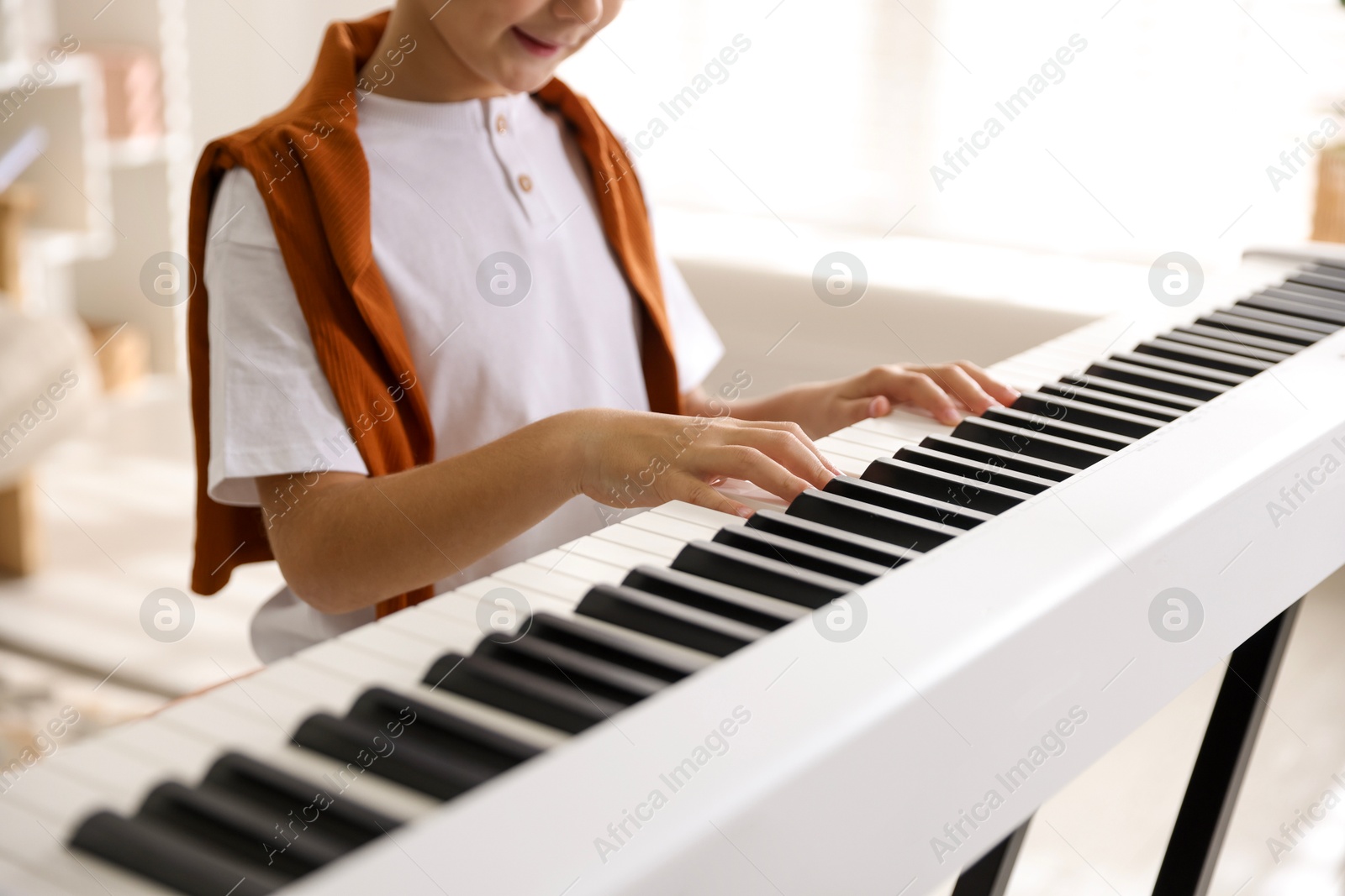 Photo of Boy playing synthesizer at home, closeup. Electronic musical instrument