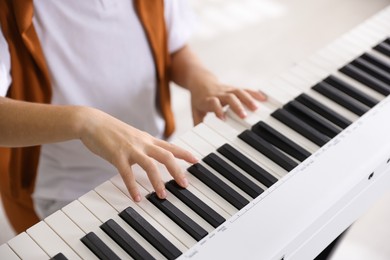 Photo of Boy playing synthesizer indoors, closeup. Electronic musical instrument