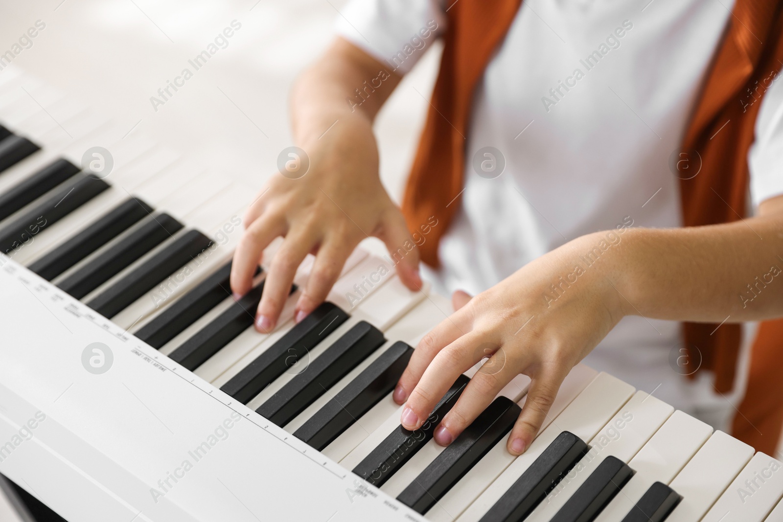 Photo of Boy playing synthesizer indoors, closeup. Electronic musical instrument