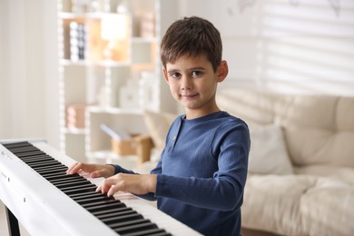 Cute boy playing synthesizer at home. Electronic musical instrument