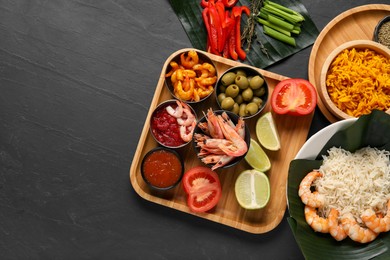 Photo of Cut banana leaves with different food and sauce on dark textured table, flat lay. Space for text