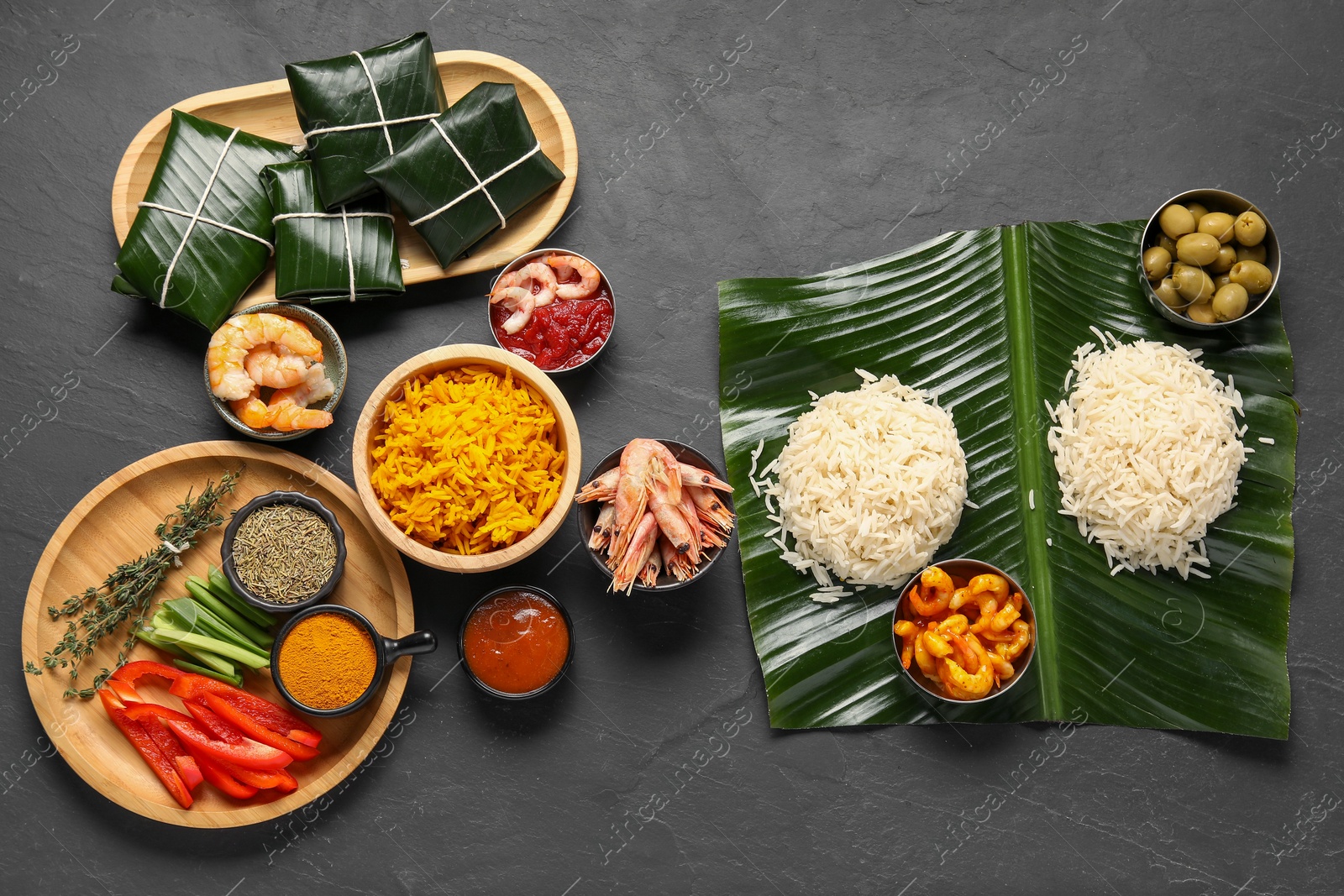 Photo of Cut banana leaves with different food, spices and sauce on dark textured table, flat lay. Healthy eco serving