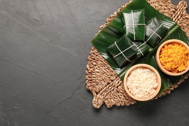 Photo of Cut banana leaves with rice on dark table, top view. Space for text