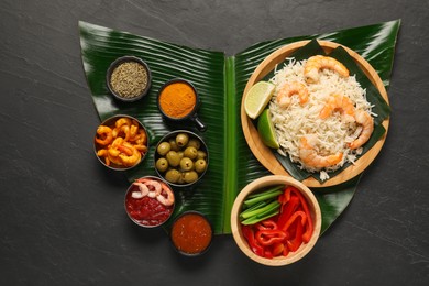 Photo of Piece of banana leaf with different food, spices and sauce on grey textured table, top view. Healthy eco serving