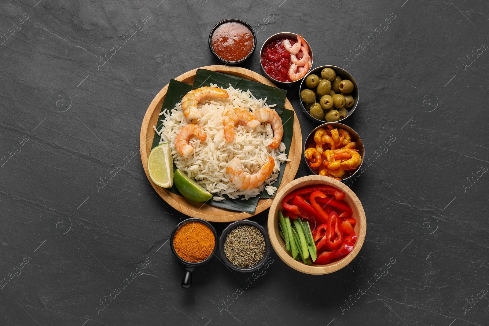 Photo of Pieces of banana leaf with rice and shrimps among other food, spices and sauce on grey textured table, flat lay