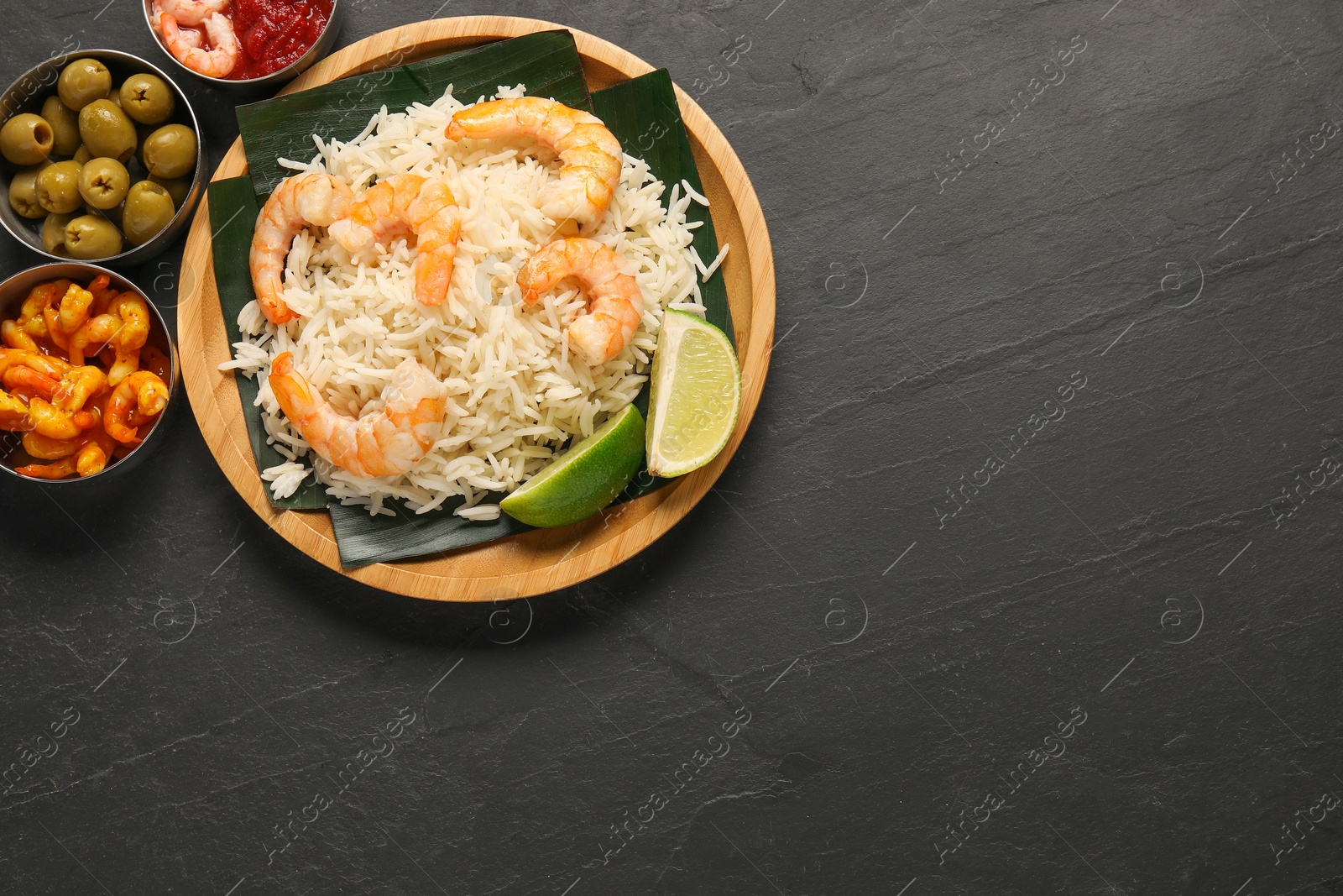 Photo of Pieces of banana leaf with rice and shrimps among other food on grey textured table, flat lay. Space for text