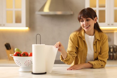 Photo of Woman using paper towels at white marble table in kitchen