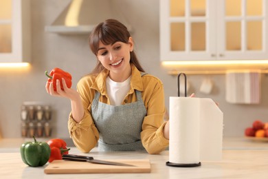 Photo of Woman with bell pepper using paper towels at white marble table in kitchen