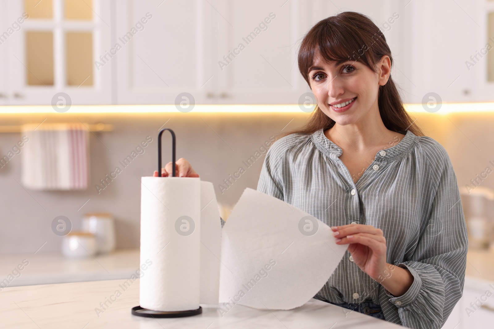 Photo of Woman using paper towels at white marble table in kitchen