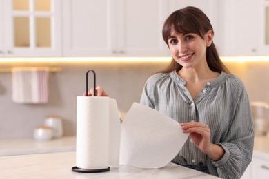 Photo of Woman using paper towels at white marble table in kitchen