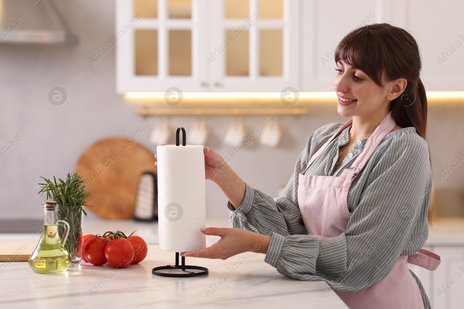 Photo of Woman using paper towels at white marble table in kitchen