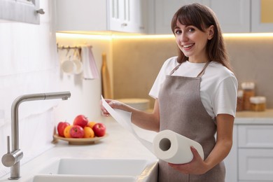 Photo of Happy woman using paper towels in kitchen