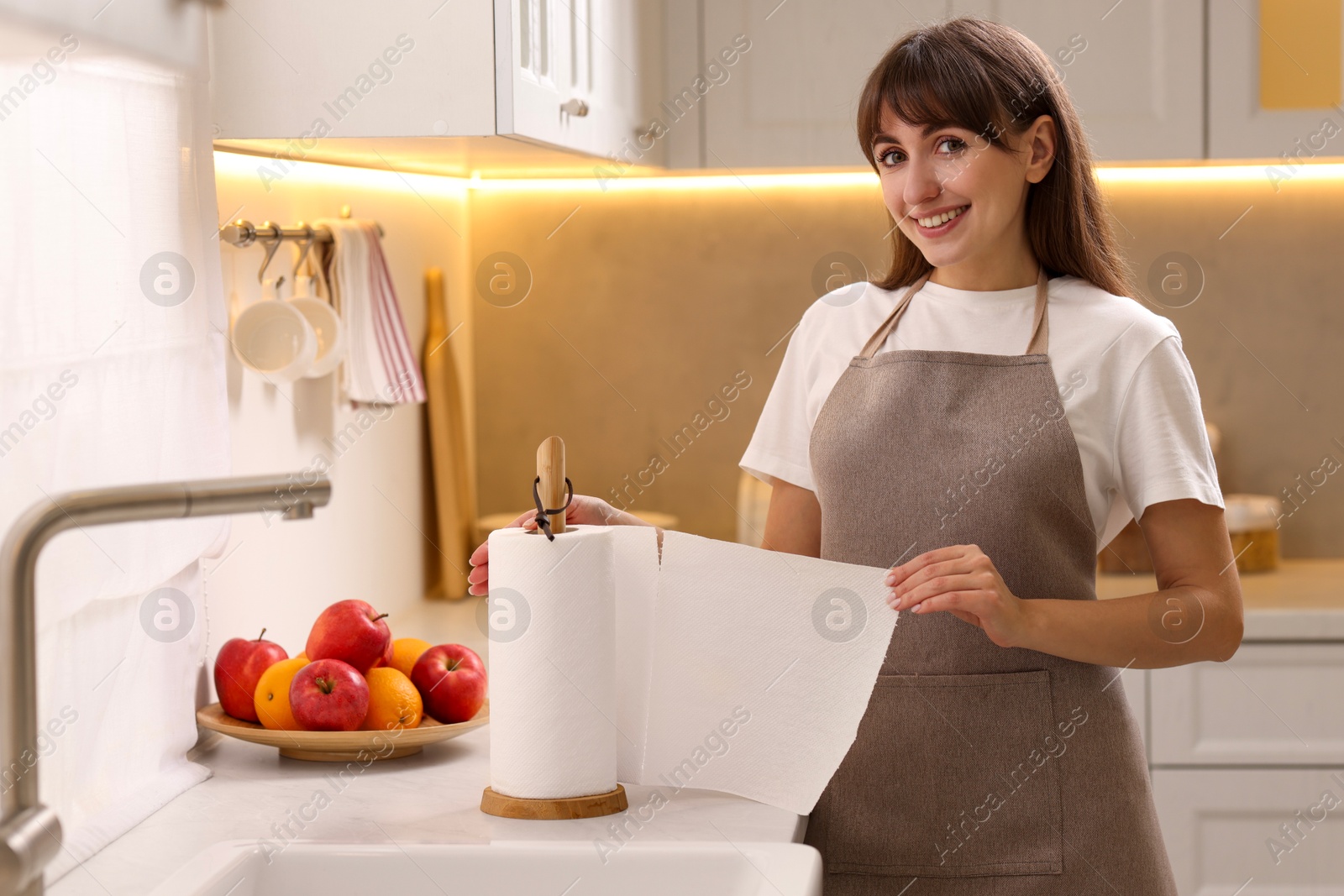 Photo of Happy woman using paper towels in kitchen